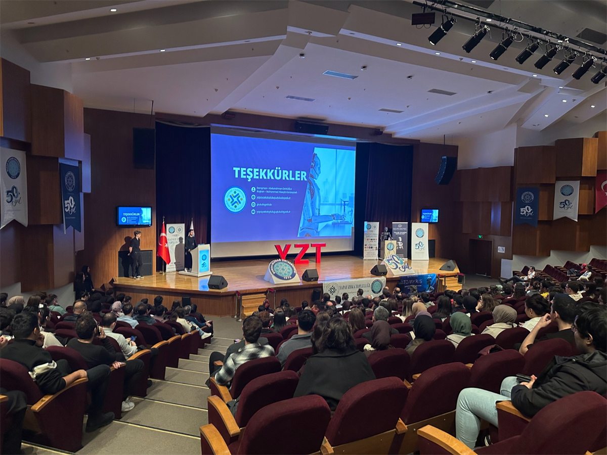 HSD Uludağ'ın önceki bir etkinliğinde konferans salonundan fotoğraf; sahnede YZT yazıyor.
